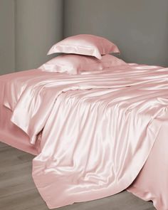 a bed covered in pink sheets and pillows