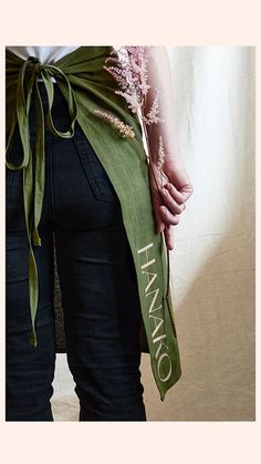 a woman with her back to the camera, wearing jeans and a green sash that says hamaro