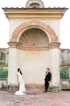 a bride and groom standing in front of an archway