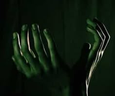 two hands reaching up in the air with green light coming from behind them on a black background