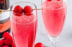 two glasses filled with raspberry champagne and garnished with cherries