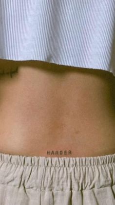 a woman's lower back with the word harder tattooed on her left side ribcage