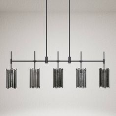 four lights hanging from the ceiling in a room with white walls and black metal bars