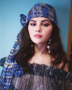 a young woman wearing a blue head scarf and matching earrings is posing for the camera