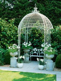 a white gazebo sitting in the middle of a garden