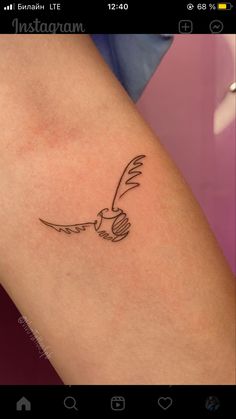 a small bird tattoo on the arm is shown in black and grey ink, with an arrow