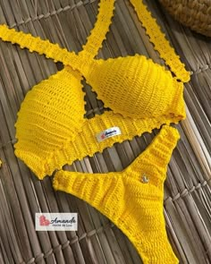 two pieces of yellow knitted bikinisuit sitting on top of a wicker mat