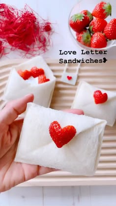 someone is holding up some small envelopes with strawberries on them and the words love letter sandwiches?