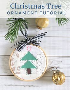 a christmas tree ornament is hanging on a white wooden wall with ornaments around it