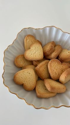 a bowl filled with heart shaped cookies on top of a white tablecloth covered table