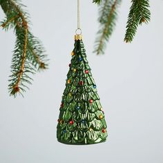 a green christmas tree ornament hanging from a branch