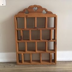 a wooden book shelf with hearts on the top and bottom shelves, against a white wall