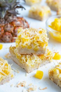 several pieces of dessert sitting on top of a white surface next to a pineapple