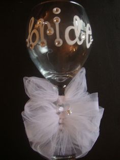 a wine glass with the word bride written on it and a white tulle bow