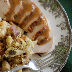 a white plate topped with meat and stuffing covered in gravy next to a fork