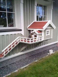 a dog house on the side of a building with stairs leading up to it's door