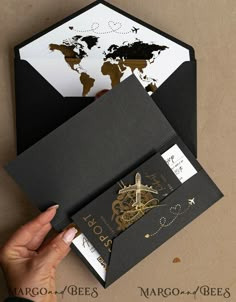 a person holding an envelope with a world map on the front and bottom, in gold foil