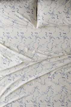 an unmade bed with white sheets and blue swirls on the comforter cover