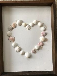 a heart made out of seashells in a shadow box