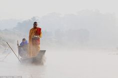 two people on a boat in the middle of a lake with mist coming from it