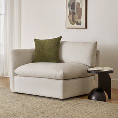 a living room with a white couch and green pillows on the back of it's chair