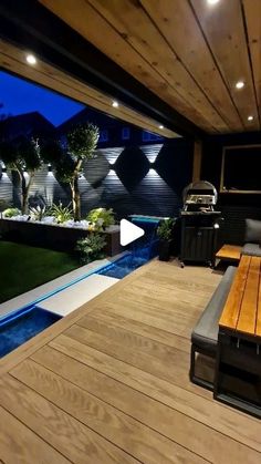 a wooden deck with benches and grills next to a swimming pool at night time