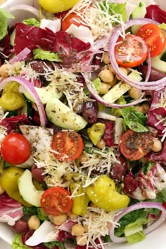 a salad with tomatoes, lettuce, olives and parmesan cheese