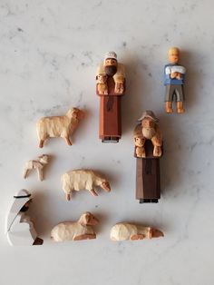 several wooden figurines are arranged on a marble counter top, including sheep and man