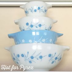 four blue and white bowls stacked on top of each other in front of a wall