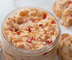 a glass jar filled with food next to biscuits