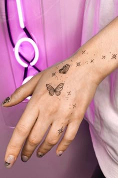 a woman's hand with a butterfly tattoo on her left wrist and stars in the middle