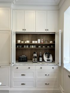 a kitchen with white cupboards and appliances on the counter top, including coffee maker