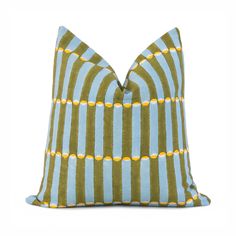 a blue and green striped pillow with yellow dots on the front, sitting on a white surface