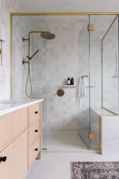 a bathroom with a walk in shower next to a white counter top and wooden cabinets