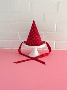 a red and white hat sitting on top of a cake stand