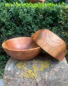 two wooden bowls sitting on top of a rock