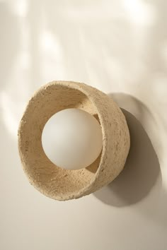 an object made out of clay sitting on top of a white surface with shadow from the wall