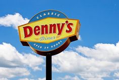 the sign for denny's diner in front of a blue sky with white clouds