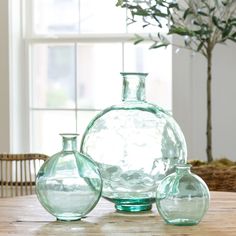 three glass vases sitting on top of a wooden table