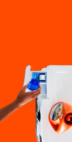 a hand is opening the door to an orange and white refrigerator with magnets on it