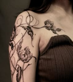 a woman's shoulder with flowers and leaves on her left arm, in black and white