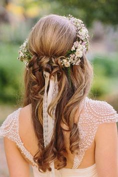 the back of a woman's head with long hair and flowers in her hair