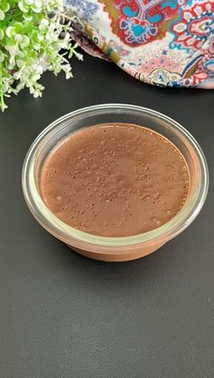 a glass bowl filled with brown liquid sitting on top of a table next to flowers