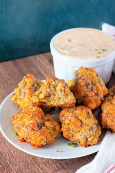 some fried food on a white plate next to a bowl of dip