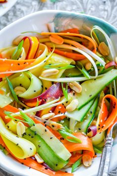 a salad with carrots, celery, and other veggies in a white bowl