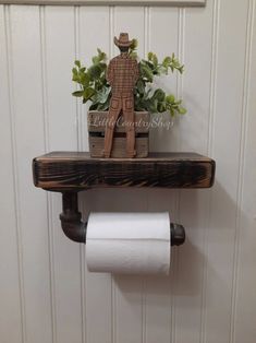 a toilet paper roll holder with a wooden man on it and a potted plant