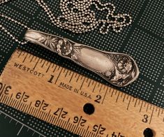 a wooden ruler with a knife on top of it next to some beads and chains