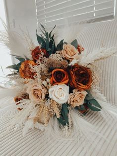 a bridal bouquet sitting on top of a white couch in front of a window