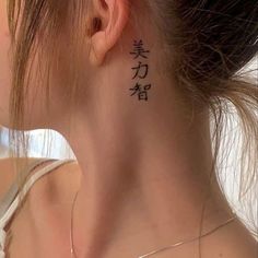 a woman with a tattoo on her neck and behind her ear is looking at the camera