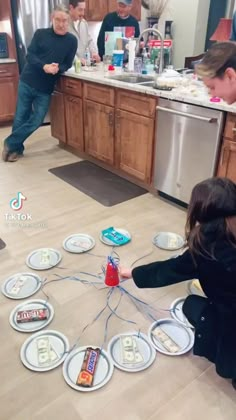 two people are playing with paper plates on the floor in front of a kitchen counter